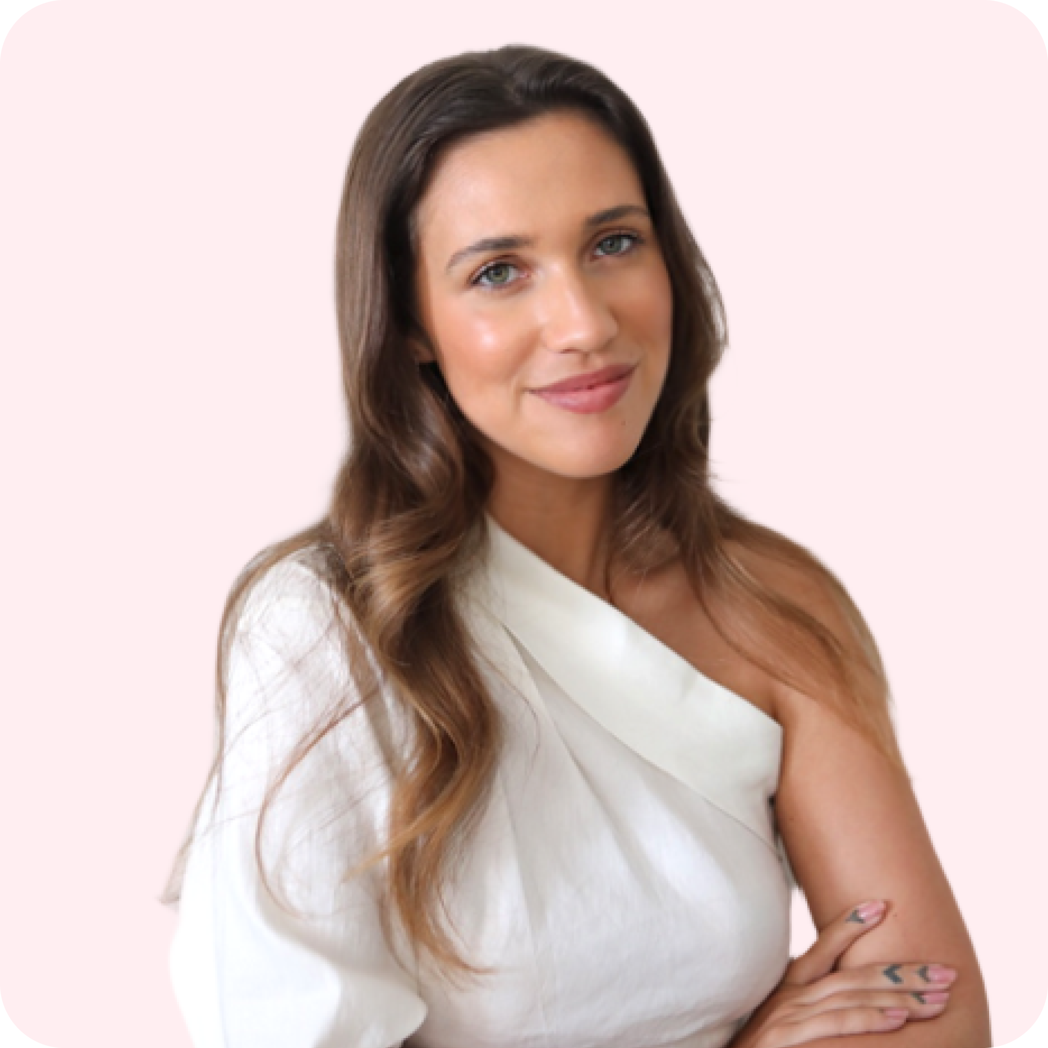 A woman with long, wavy brown hair, wearing a white, off-shoulder top, smiles with her arms crossed against a light pink background, representing a social media scheduler | plannthat.com